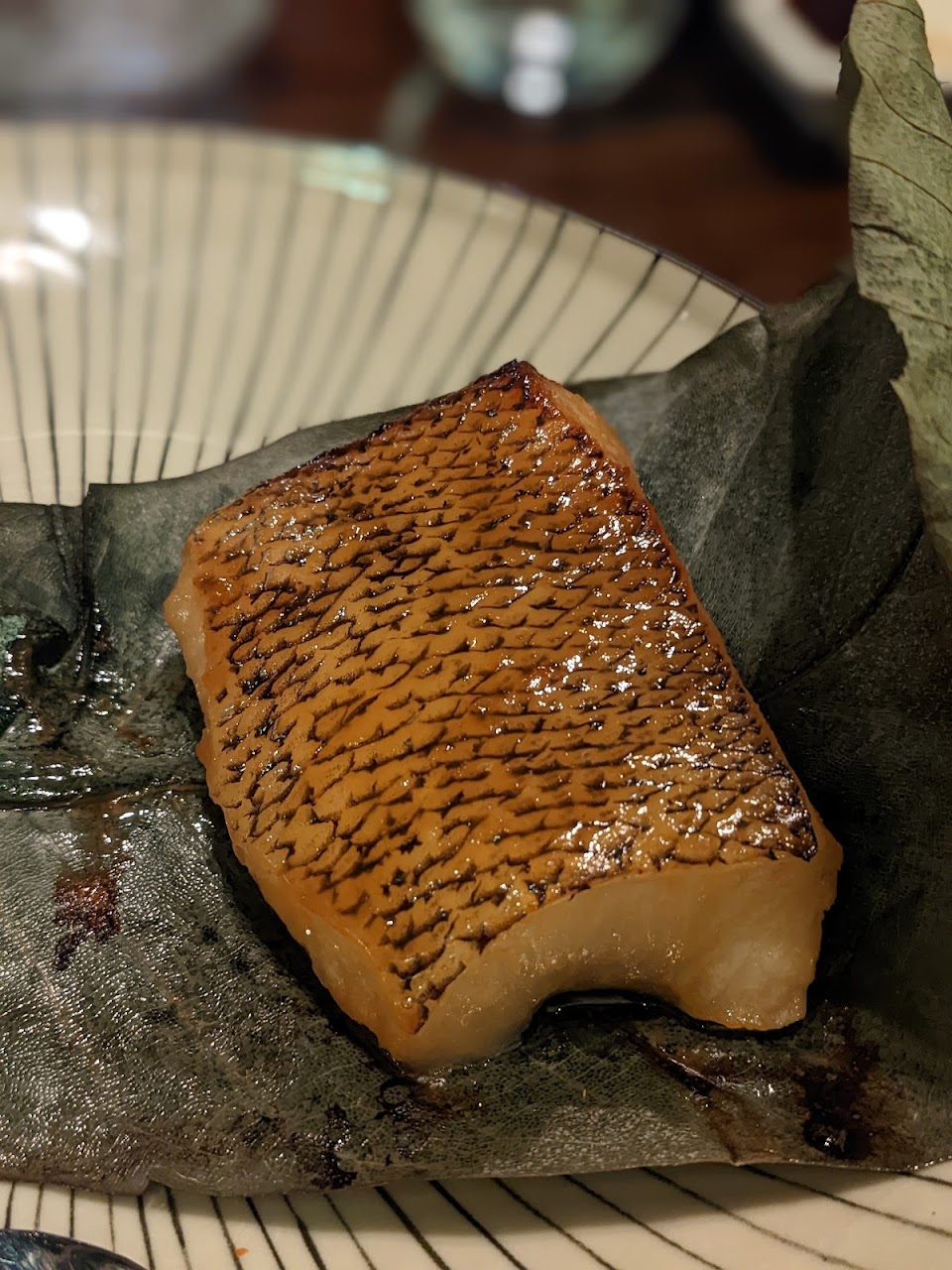 Grilled fish dish served on a dark plate at Saké Restaurant & Bar